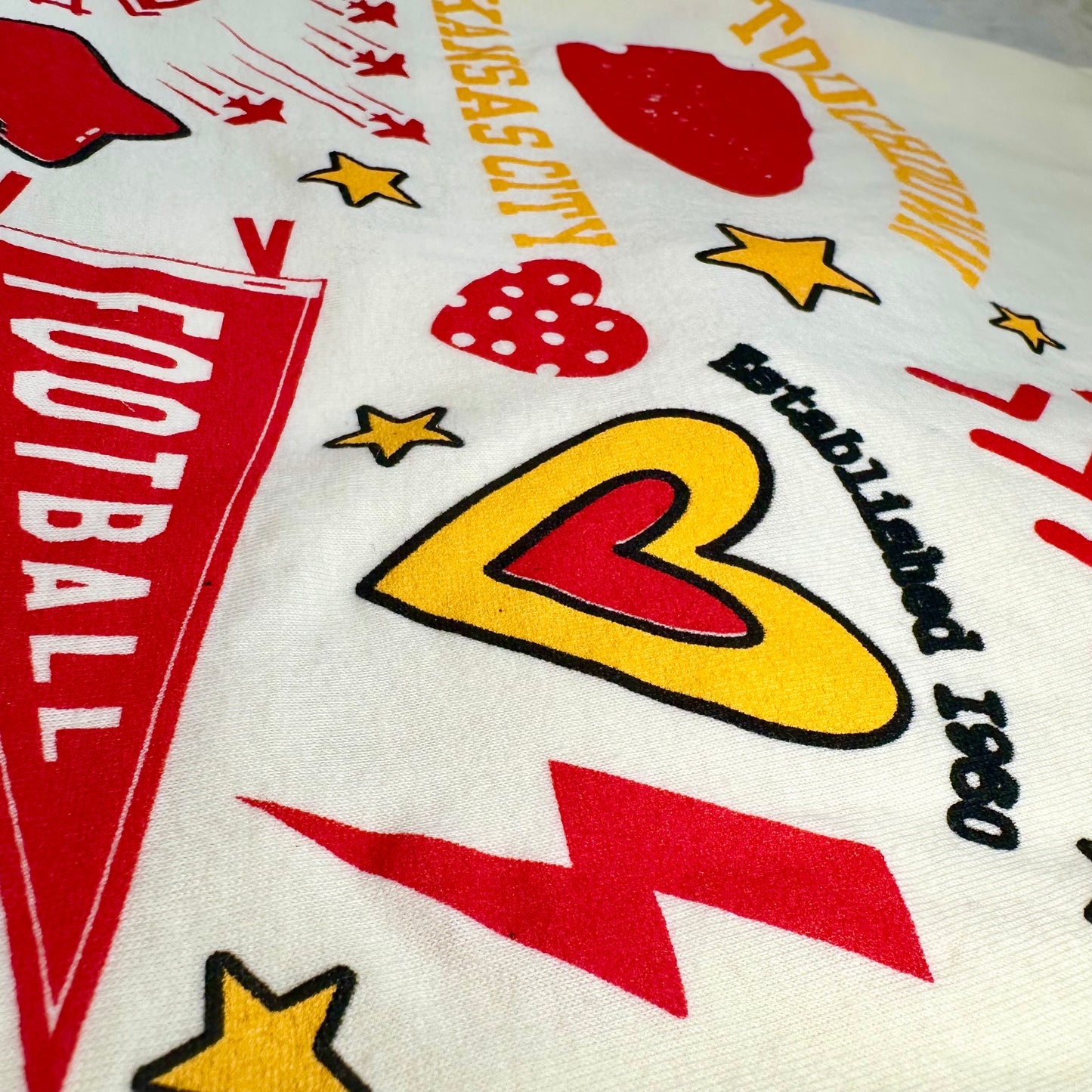 Close-up of a tshirt back with sports-themed graphics including stars, hearts, and text.