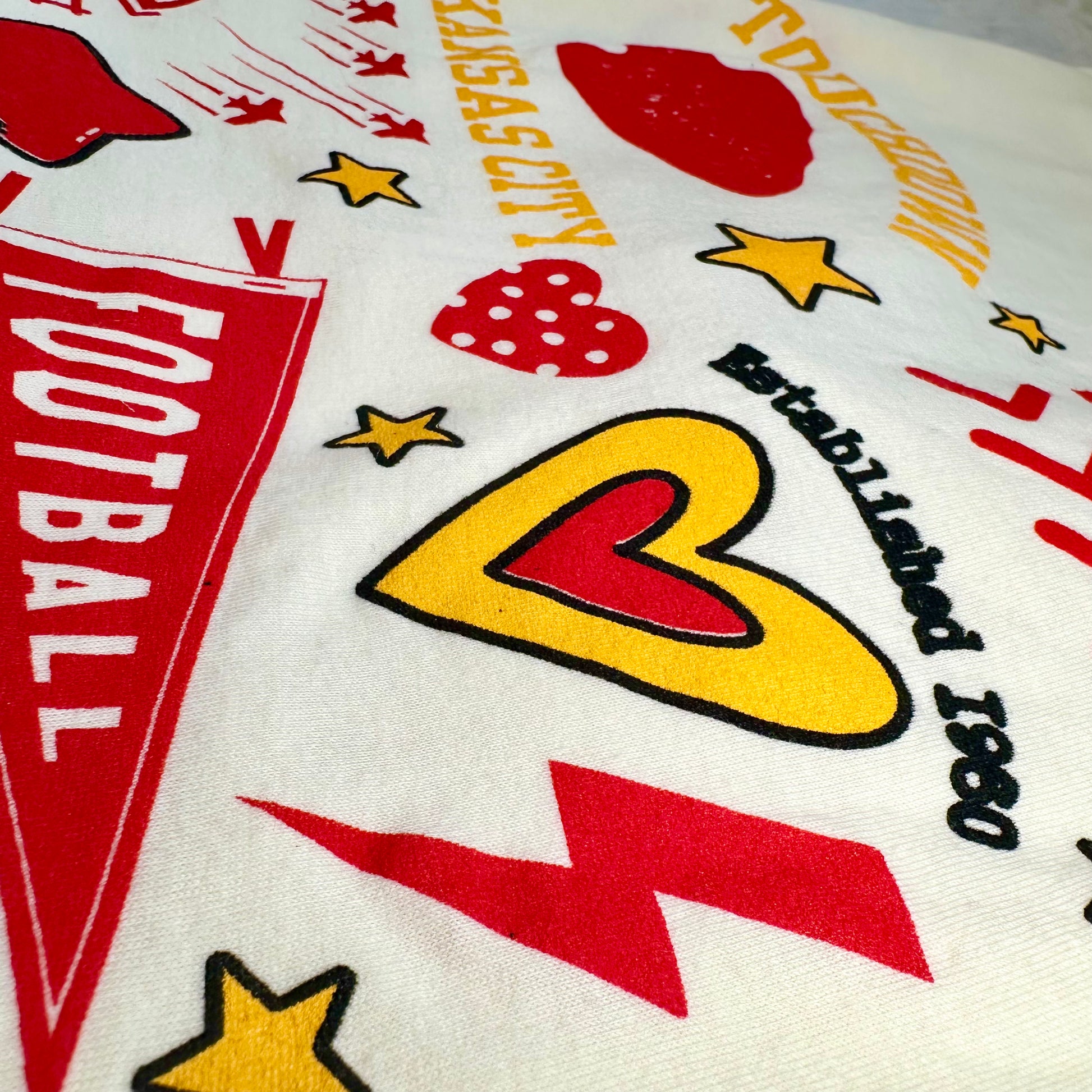 Close-up of a tshirt back with sports-themed graphics including stars, hearts, and text.