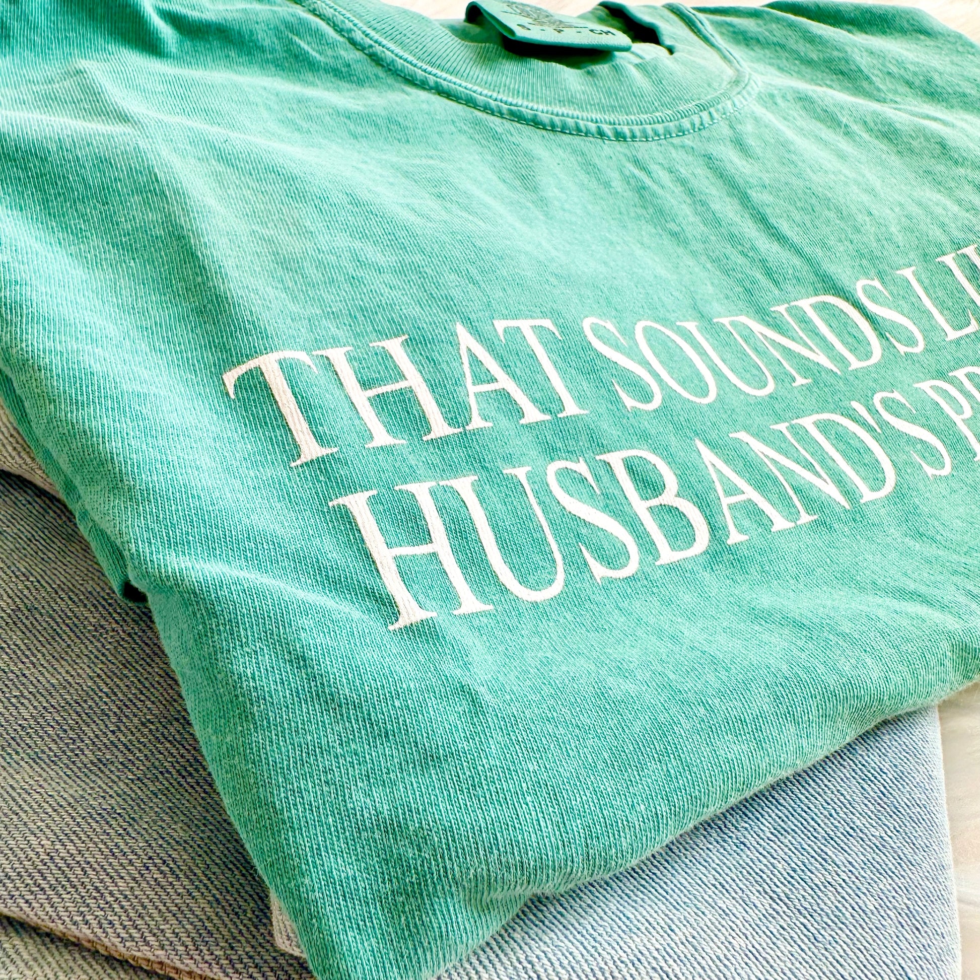 Green t-shirt with white text on a gray surface